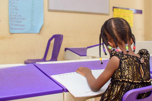 Nigerian school girl facing board, working intently on her school work