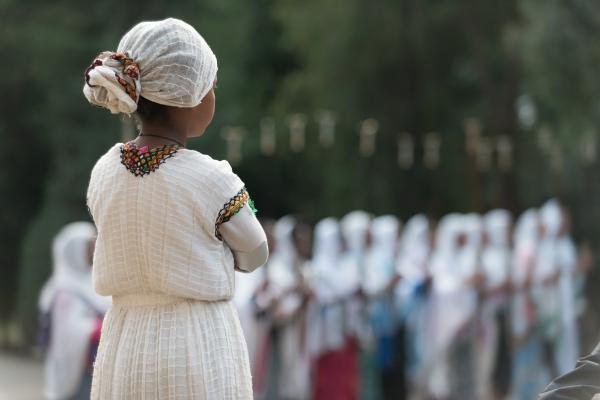Young Ethiopian woman wearing traditional dress watches crowd from a distance