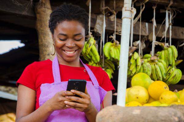 Nigerian woman working at market uses mobile phone