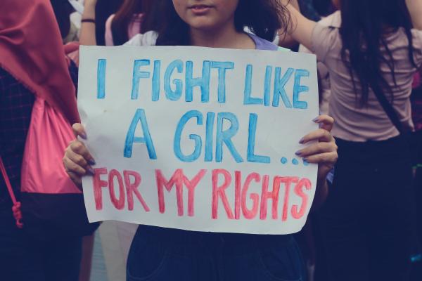 Young woman holds sign at protest which reads: I fight like a girl for my rights