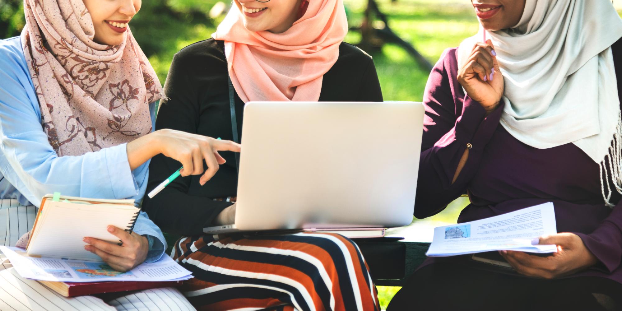 Three young Muslim women use laptop in work meeting