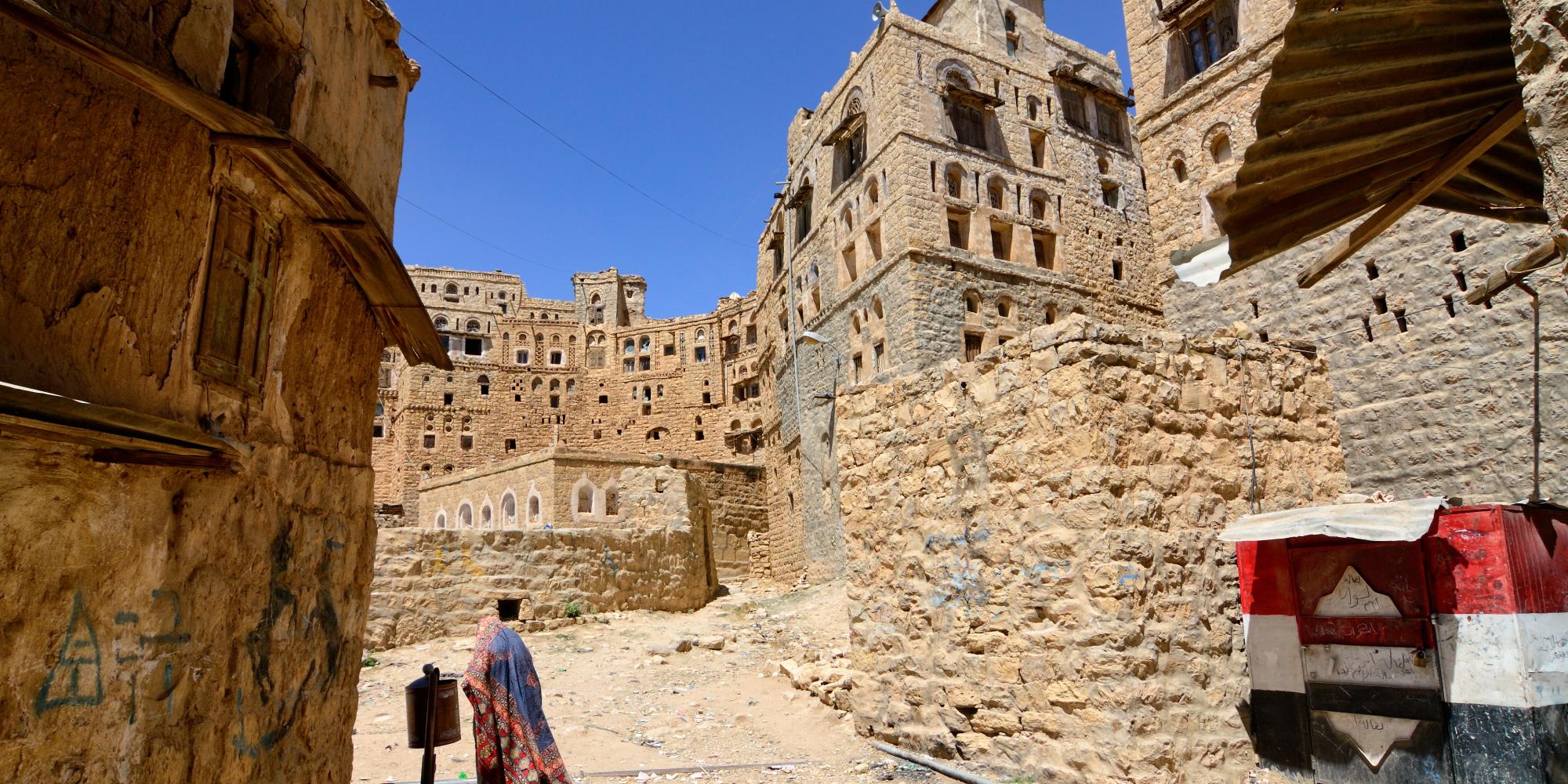 Woman walks through streets of mountain village Habbabah, Yemen