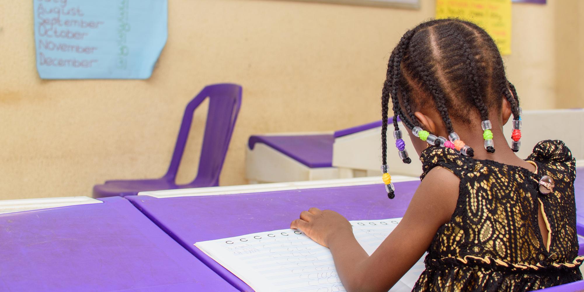 Nigerian school girl facing board, working intently on her school work