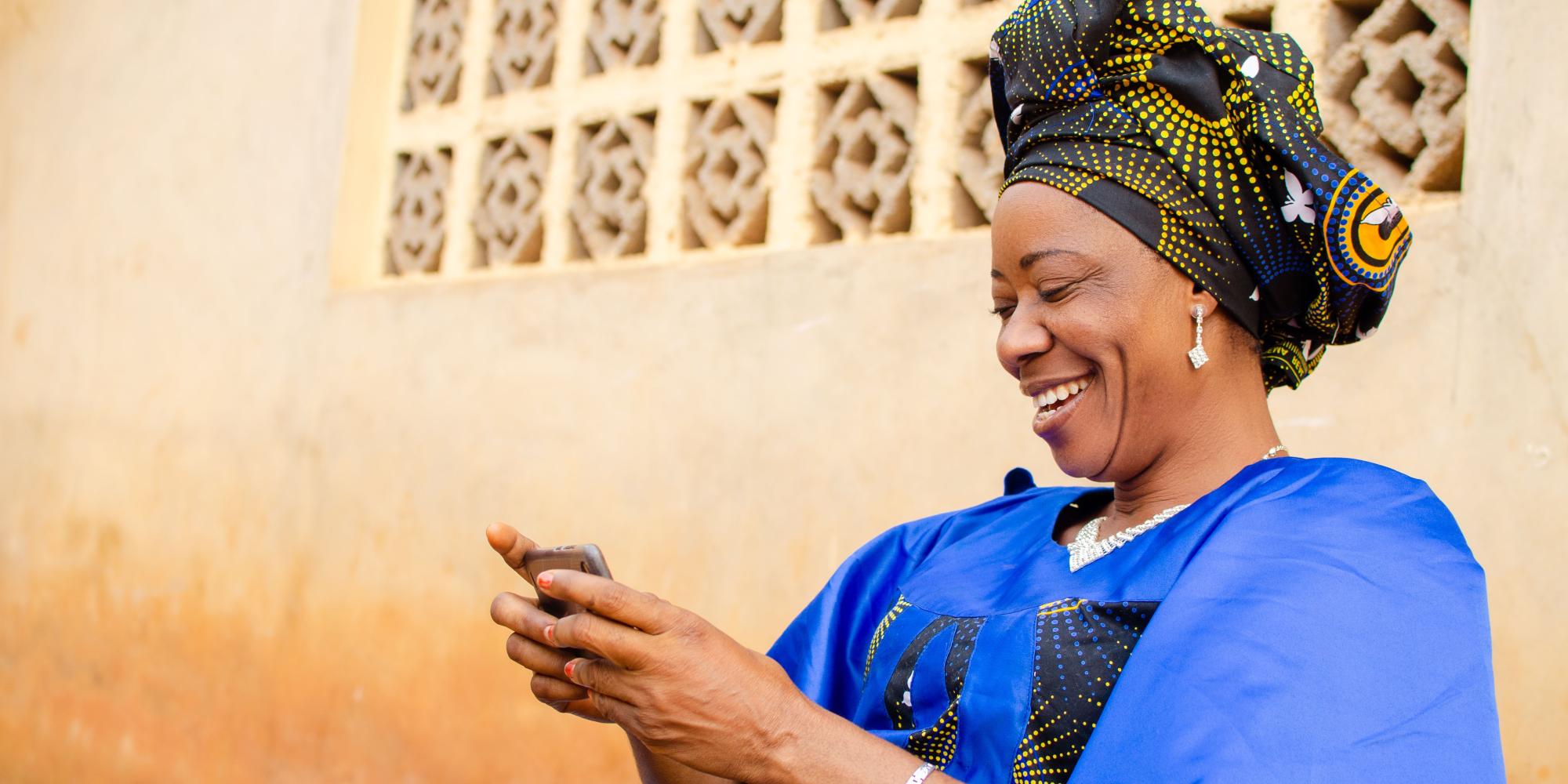 Nigerian woman smiling while using mobile phone